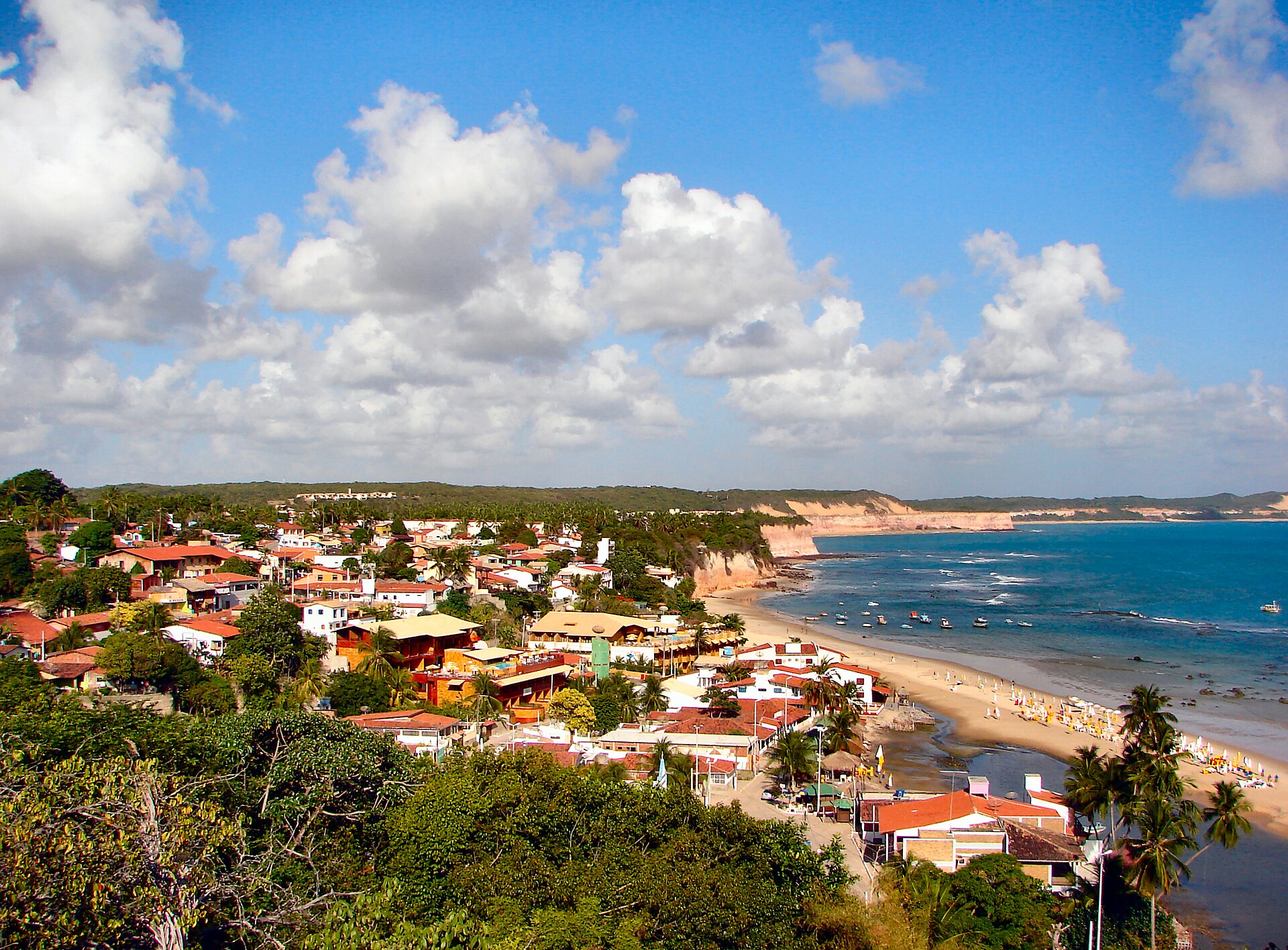Praia de Pipa vista de cima: vilarejo, faixa de areia, falésias e mar.